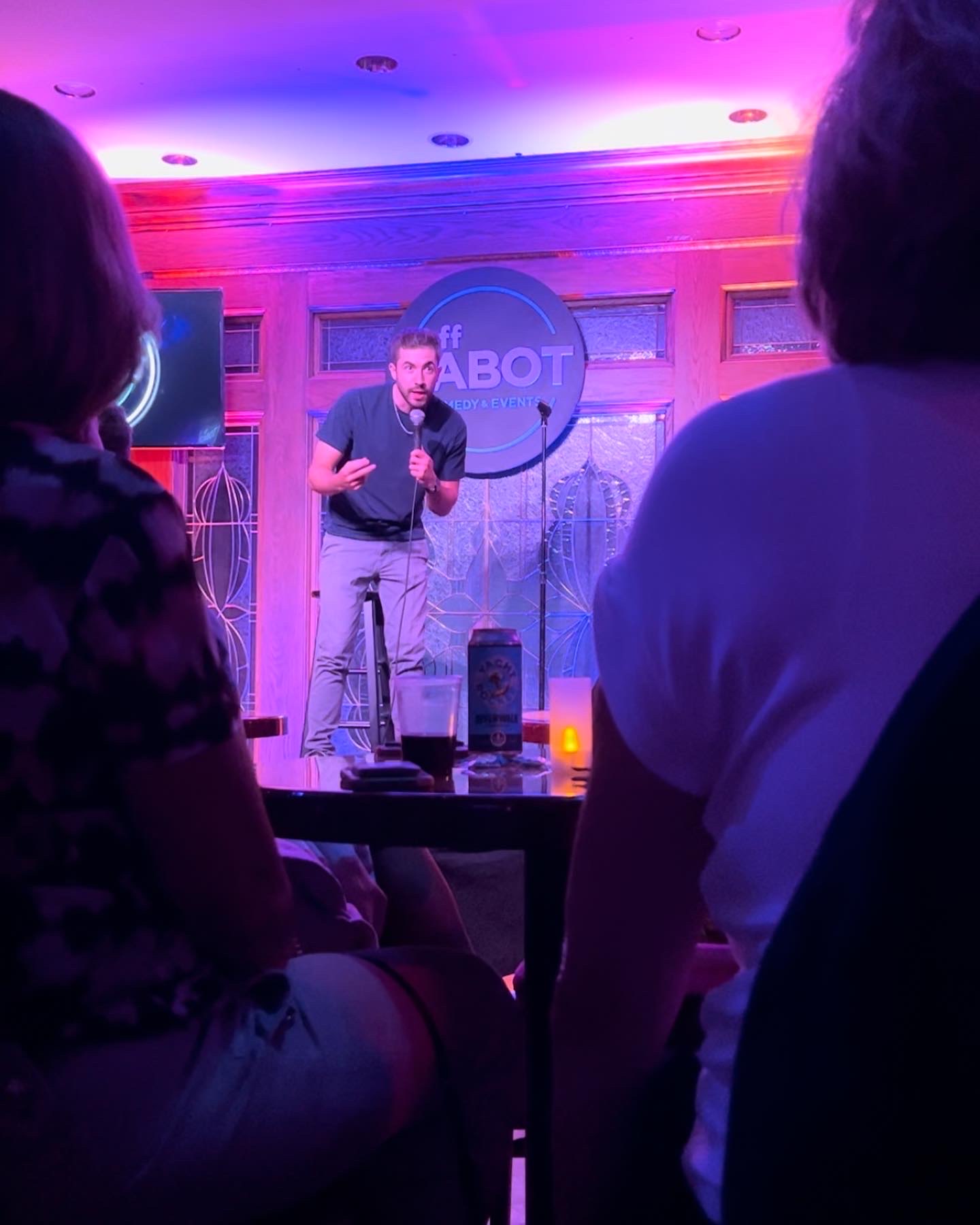 DiMaggio performing stand-up under pink and blue stage lights